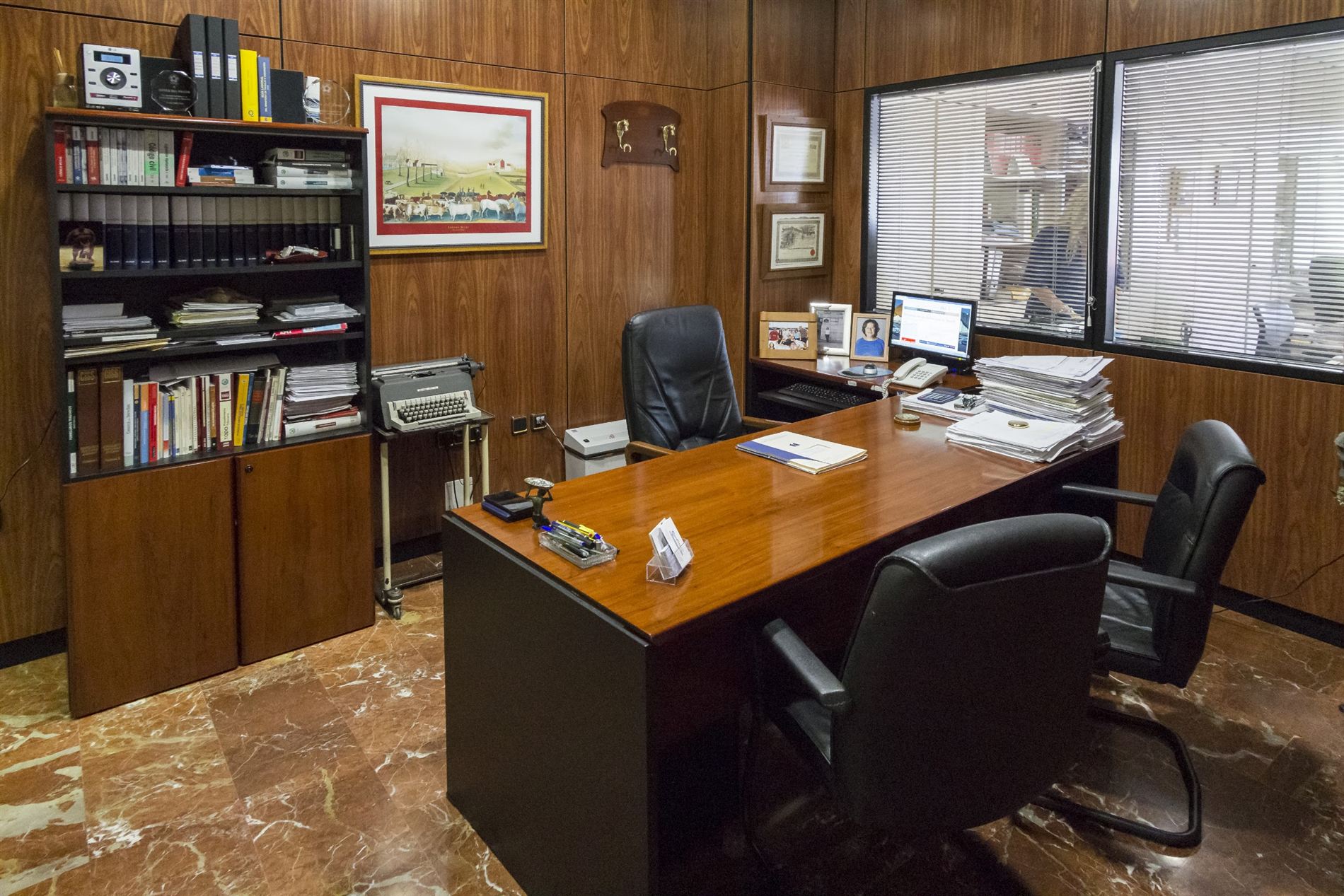 Despacho de Asesoría Cofise: mesa de trabajo, tomos de legislación y una máquina de escribir junto al ordenador.
